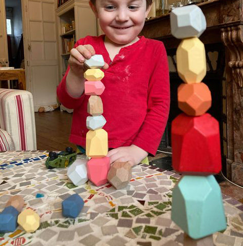 Child playing with the wooden educational blocks of the Montessori Game Petit Menhir