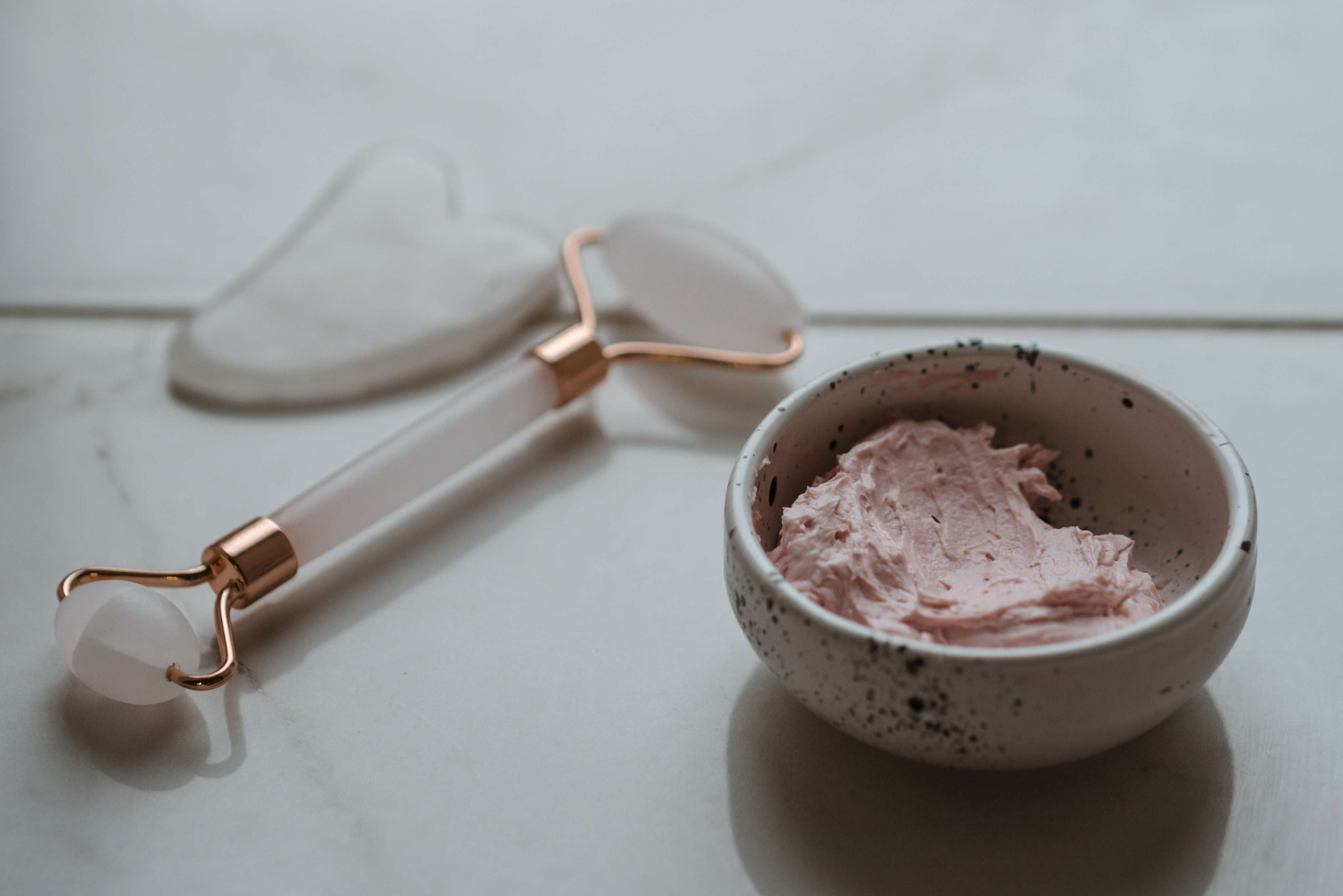 Facial Roller and Guasha with Pink Cream in Bowl for Facelift Exercises