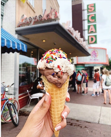 woman's hand holding ice cream cone in front of Leopold's ice cream