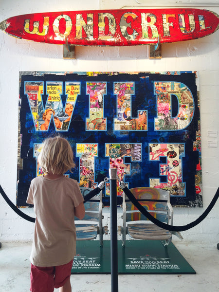 Child staring at a wall of large scale art that says Wild Life