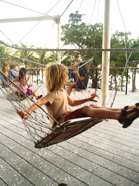 Boy swinging from art installation swings on terrace of PAMM