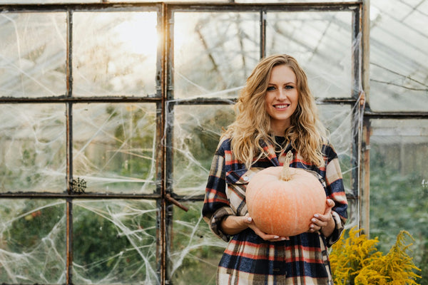Woman holding a pumpkin in a greenhouse
