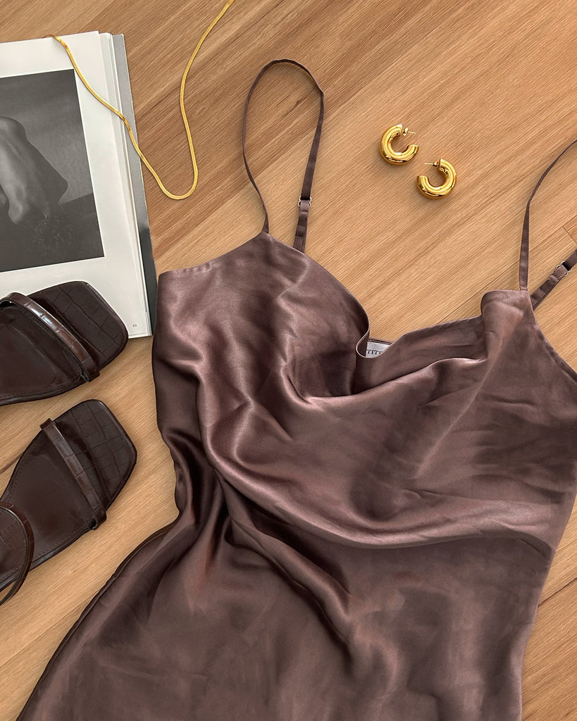 Flat lay of brown slip dress, brown mule sandals, gold hoop earrings and gold necklace.