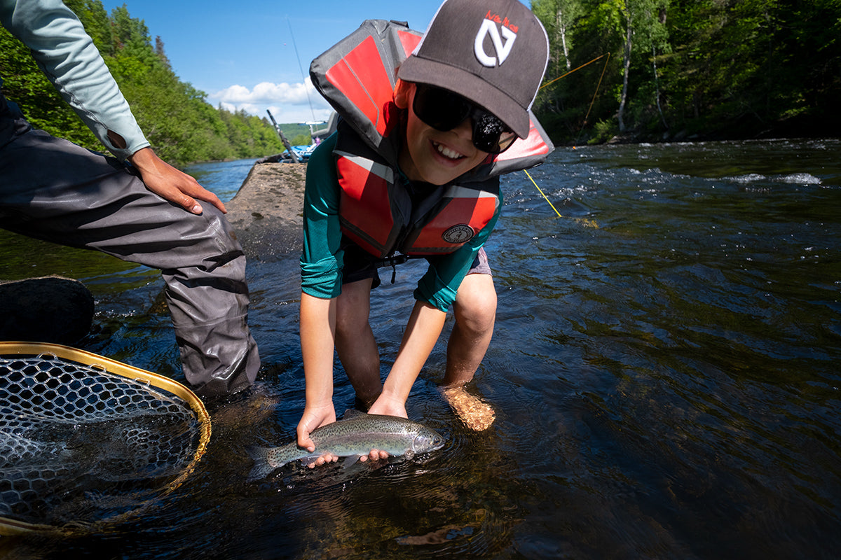 Young fisherman holds a rainbow trout he just caught