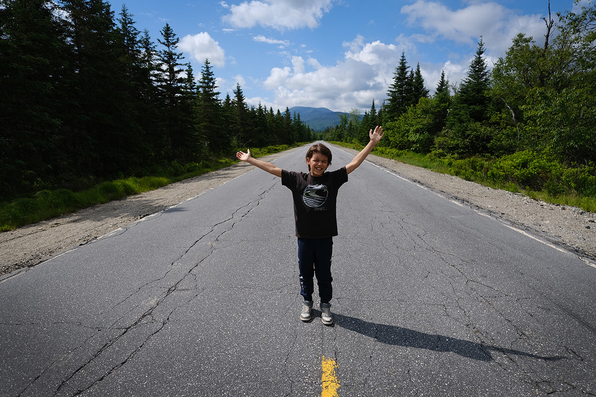 Classic road trip photo standing in the road with mountains in background