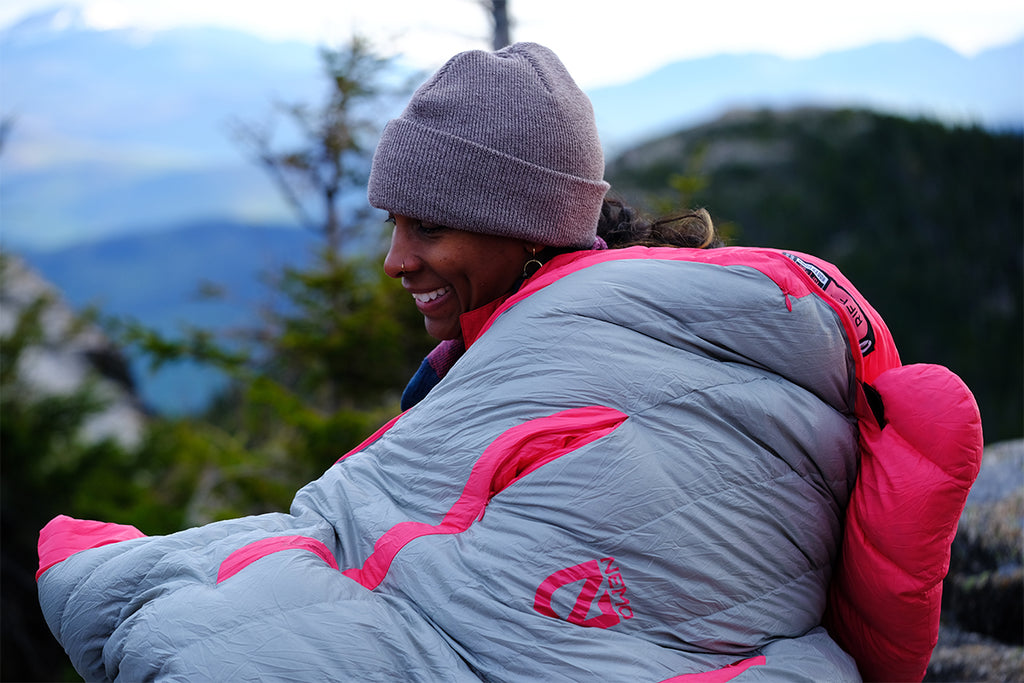 Woman sitting outside while huddled inside her sleeping bag