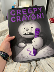 Creepy Crayon Book, black and white bunny holds an oversized purple crayon and looks scared.