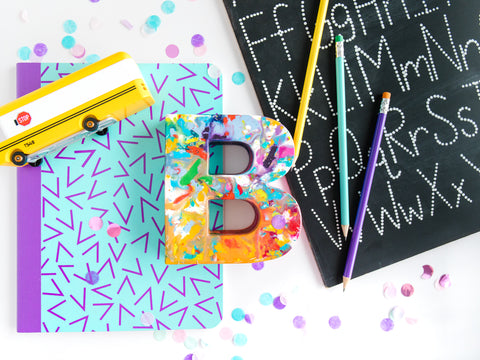 Young girls will love the oversized crayon letter B, Original Rainbow Crayon Gift for Back to School. This colorful back to school display includes a wooden bus, colorful graphic notebook, handwriting chalkboard in addition to our rainbow crayon.