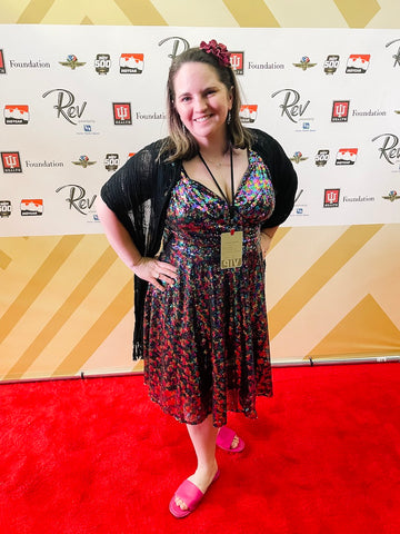 Women posing on red carpet at Rev Indianapolis event for the Indy 500 in a rainbow colored dress.