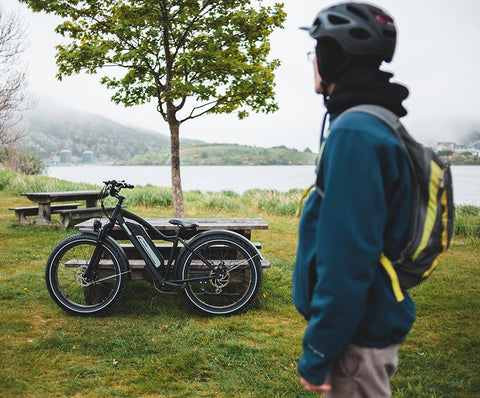 Mann mit Fahrradausrüstung im Vordergrund und E-Bike im Hintergrund