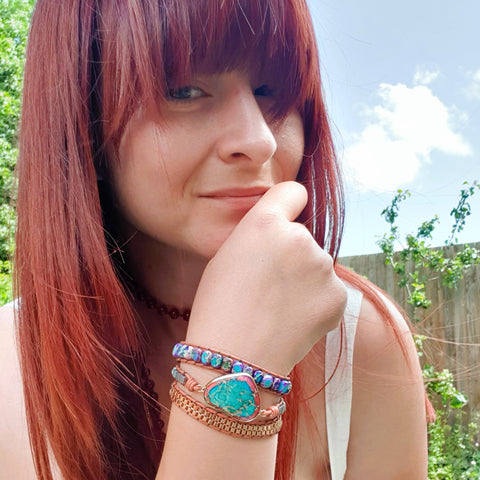 A person wearing a flowing white dress adorned with gemstone jewelry including a bracelet and a mala necklace. The image is captured for the blog post titled 'Embrace the magic of the Summer Solstice, celebrating the light within.