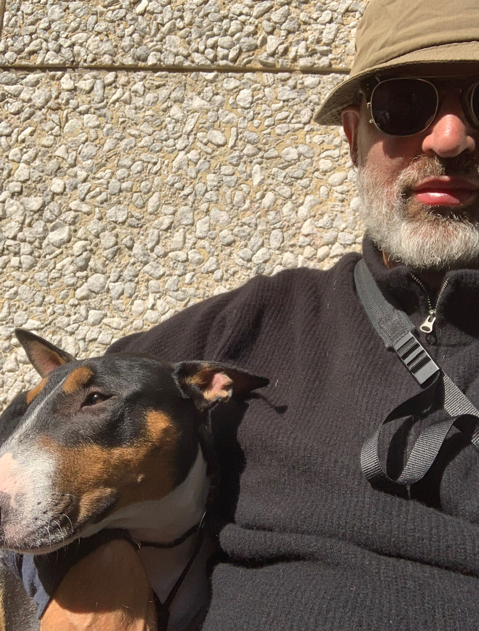 Sasa Antic sitter med sin hund Novak. Sasa har svarta solglasögon och grön hatt.