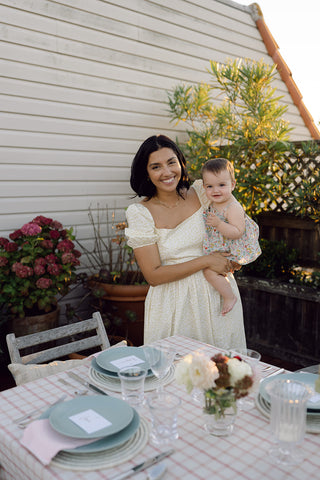 woman holding a baby by a set outdoor table