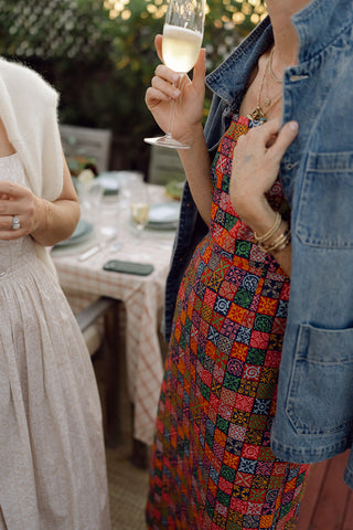 dinner party guest in a red print dress holding a glass of champagne