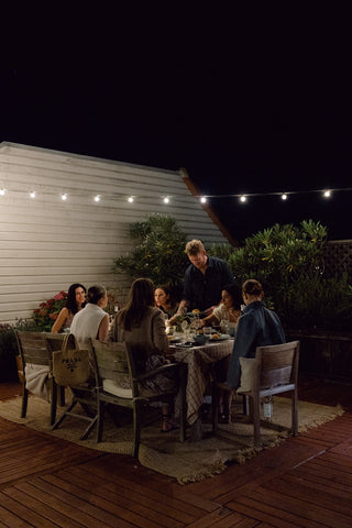 outdoor dinner party at night. friends are sitting at the table enjoying dinner