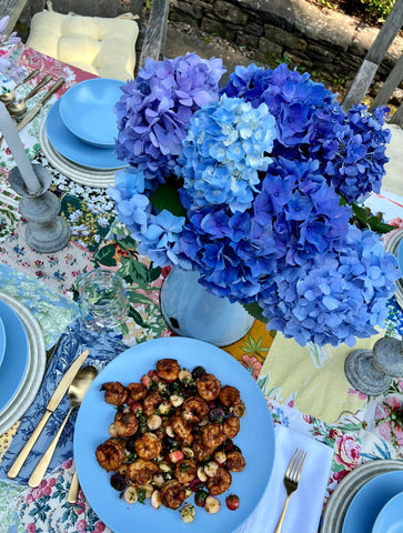 Food on blue ceramic plates and blue hydrangeas in a vintage blue pitcher. 