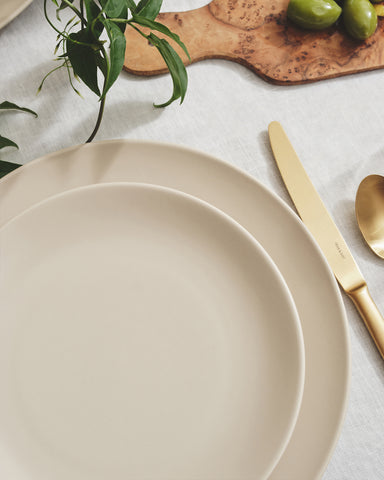 Dune ceramic plates set on a table with matte gold flatware.