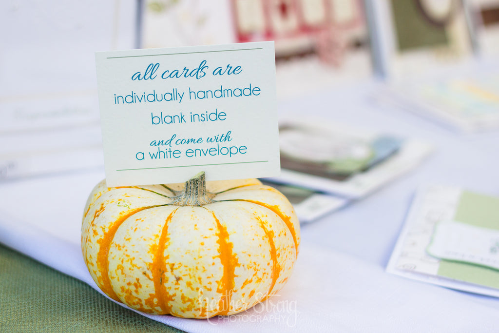 Small pumpkin holding a card with information at a craft fair booth