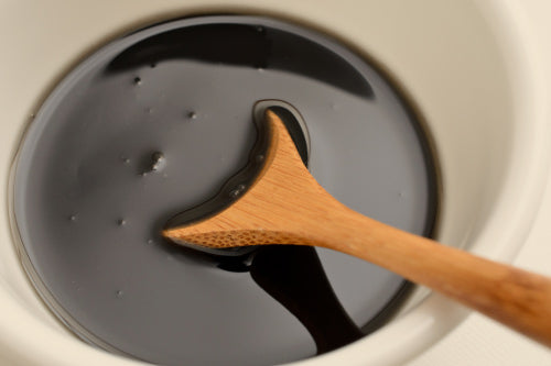 a cup of shilajit liquid in a cup with a wooden spoon inside