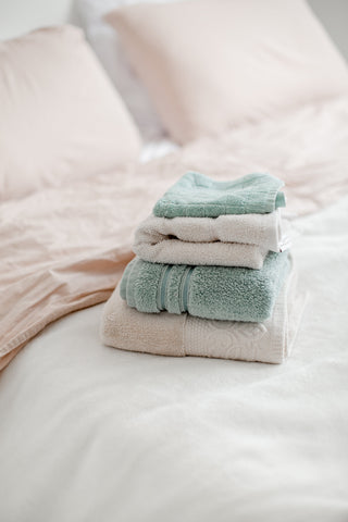 towels stacked on a bed, pillowcases