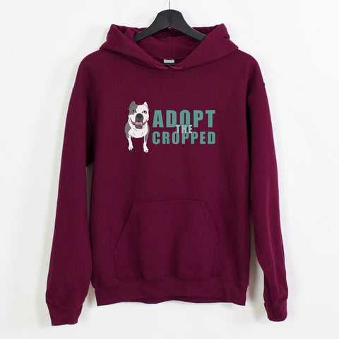 A maroon sweatshirt with an illustration of a grey and white bully with cropped ears with 'adopt the cropped' in teal text