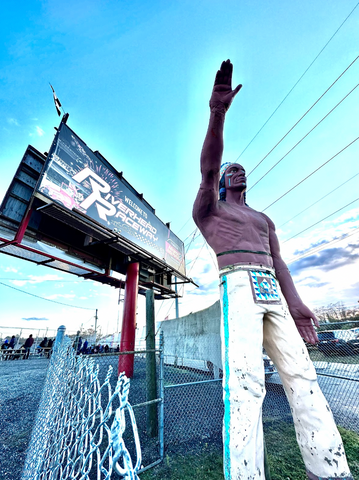 An enormous statue of a Native American (stereotype) outside Riverhead Raceway on Long Island, with the track's welcome sign at left