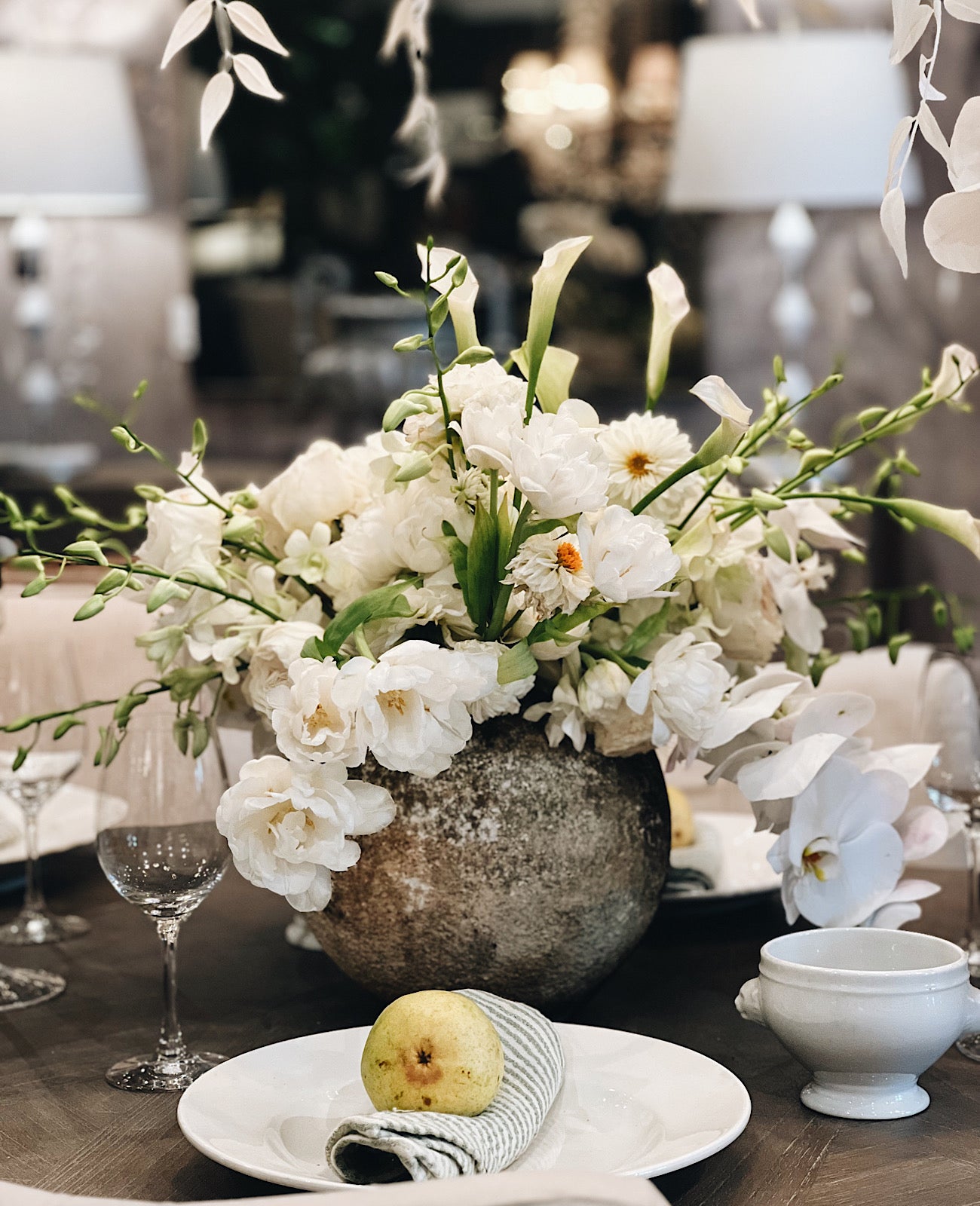 A tablescape featuring an antique stone vase and beautiful floral display.