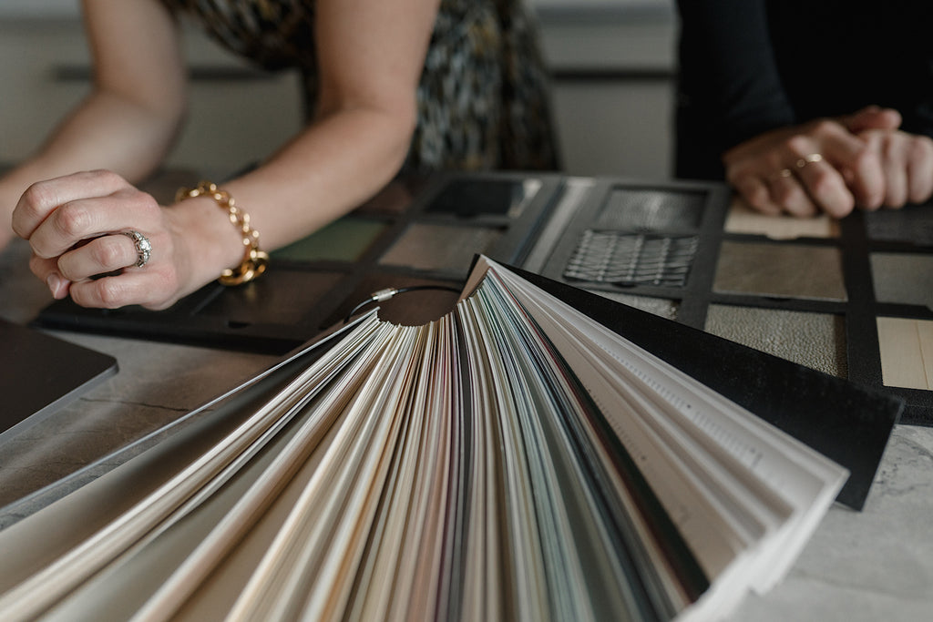 A countertop displays paint selections and tile finishes that are being selected by interior designer Katie Stephenson and a member of her design team.