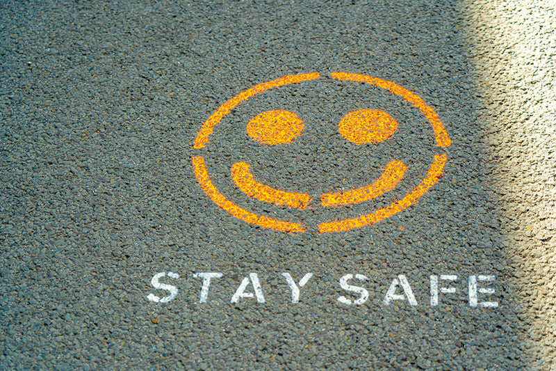 A smiley face and “Stay safe” spray-painted onto the road