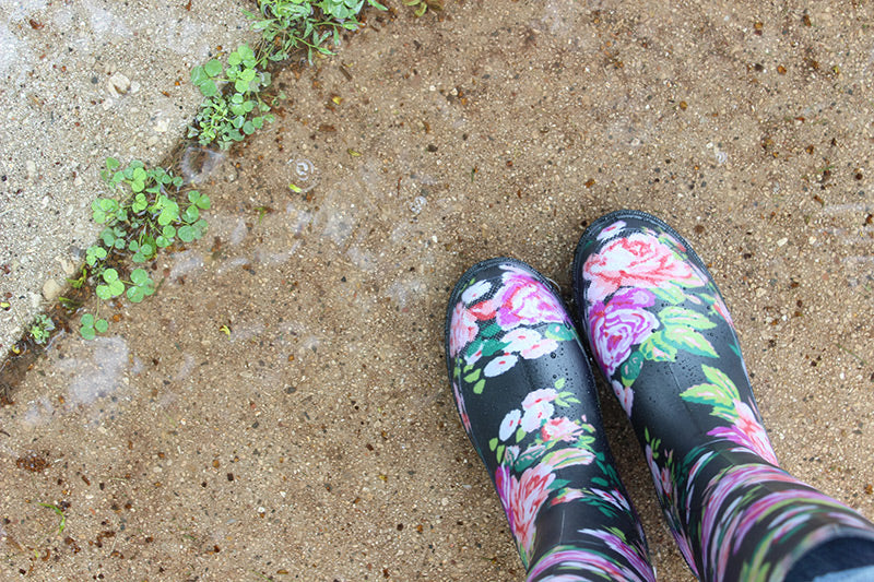 Someone in wellies standing next to weeds. 