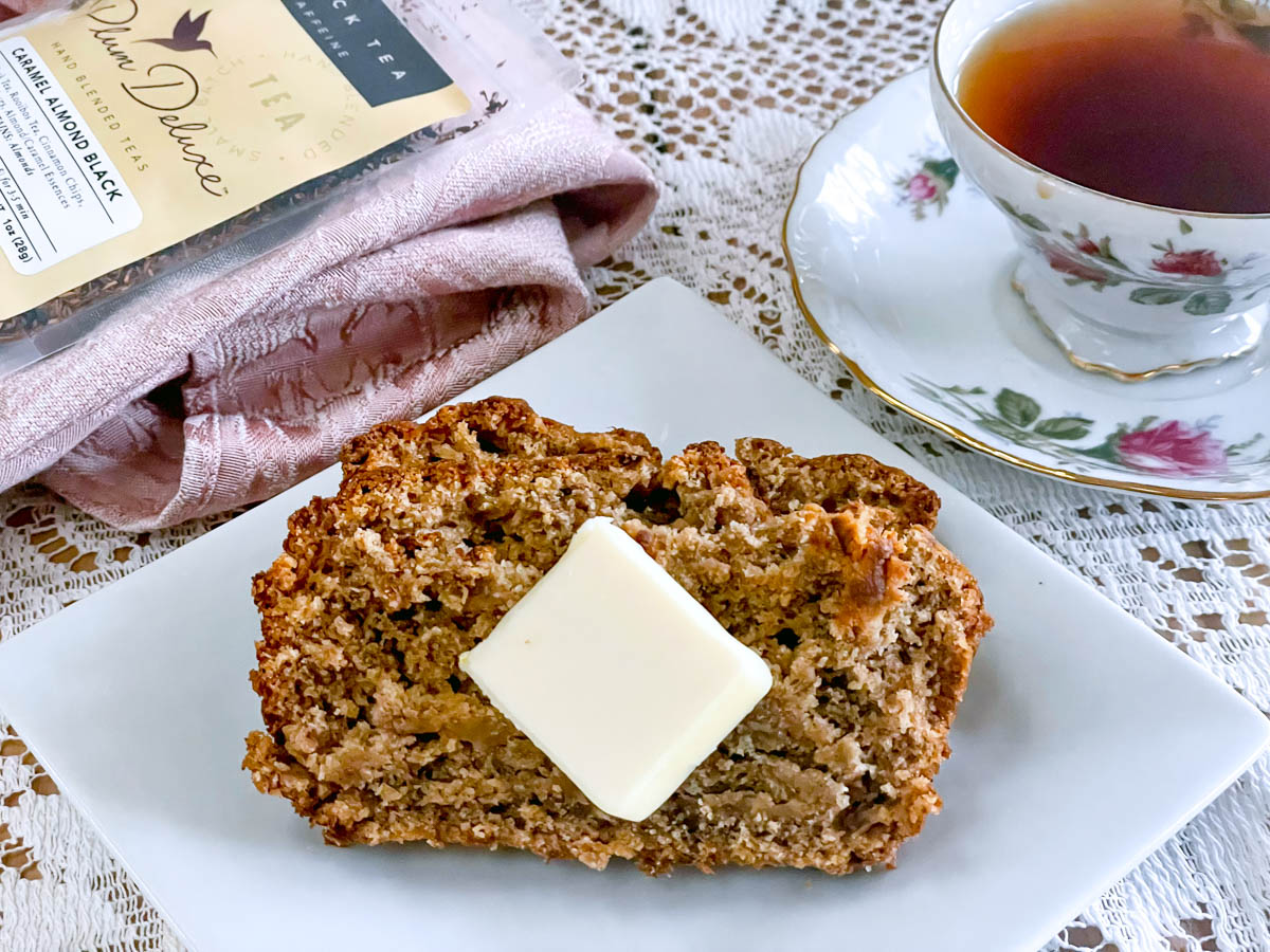 A buttered slice of apple banana bread paired with a cup of tea.