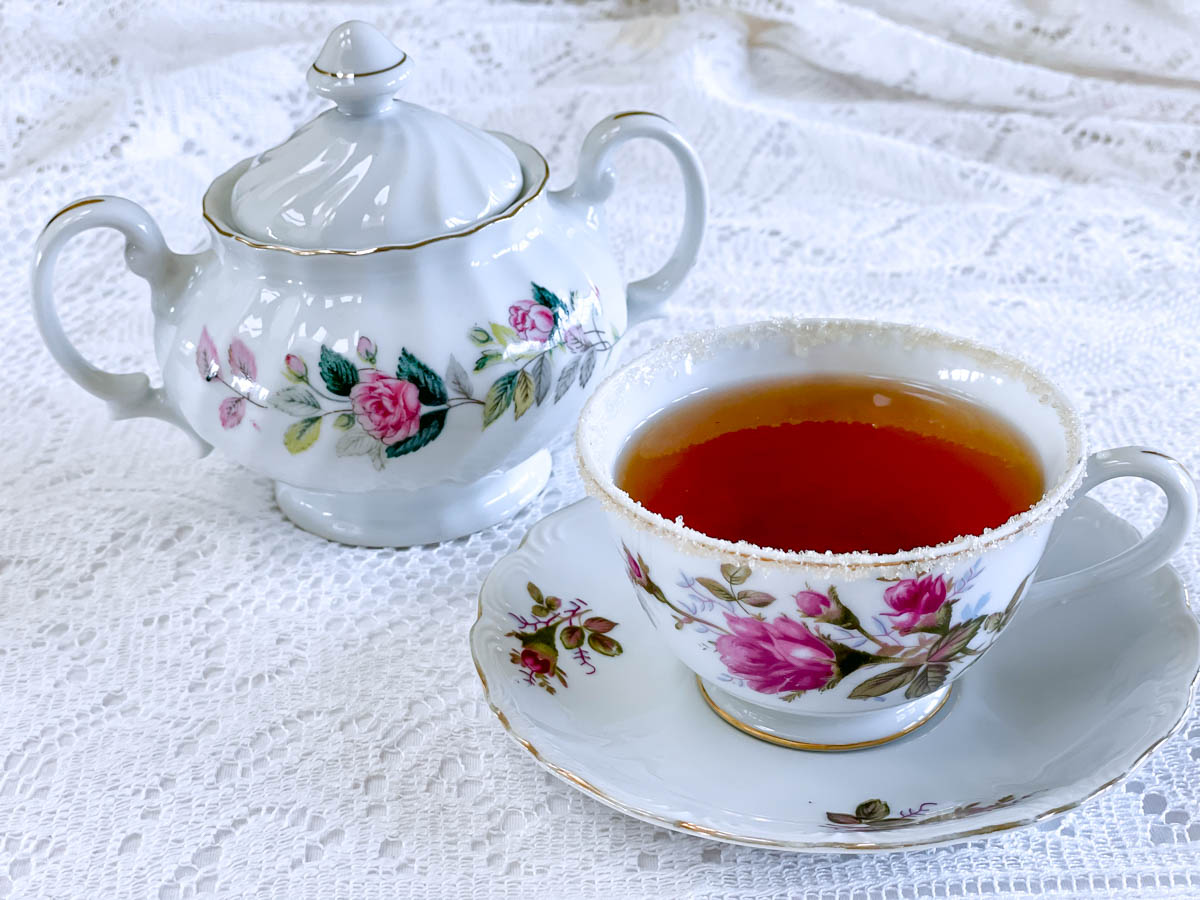 A sugar-rimmed cup of tea with a matching teapot.