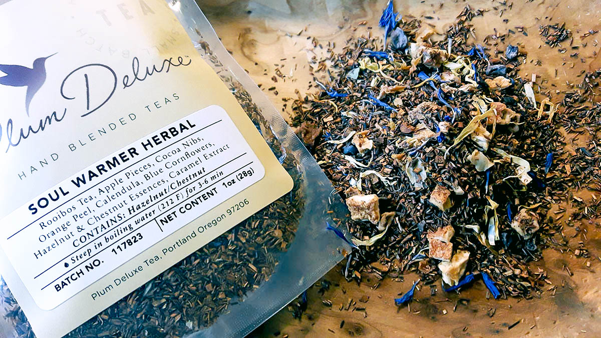 Soul Warmer herbal loose-leaf tea spread out on a wooden surface.