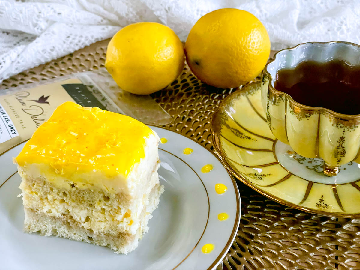 A plated lemon curd tiramisu with accompanying earl grey tea and a backdrop of lemons.