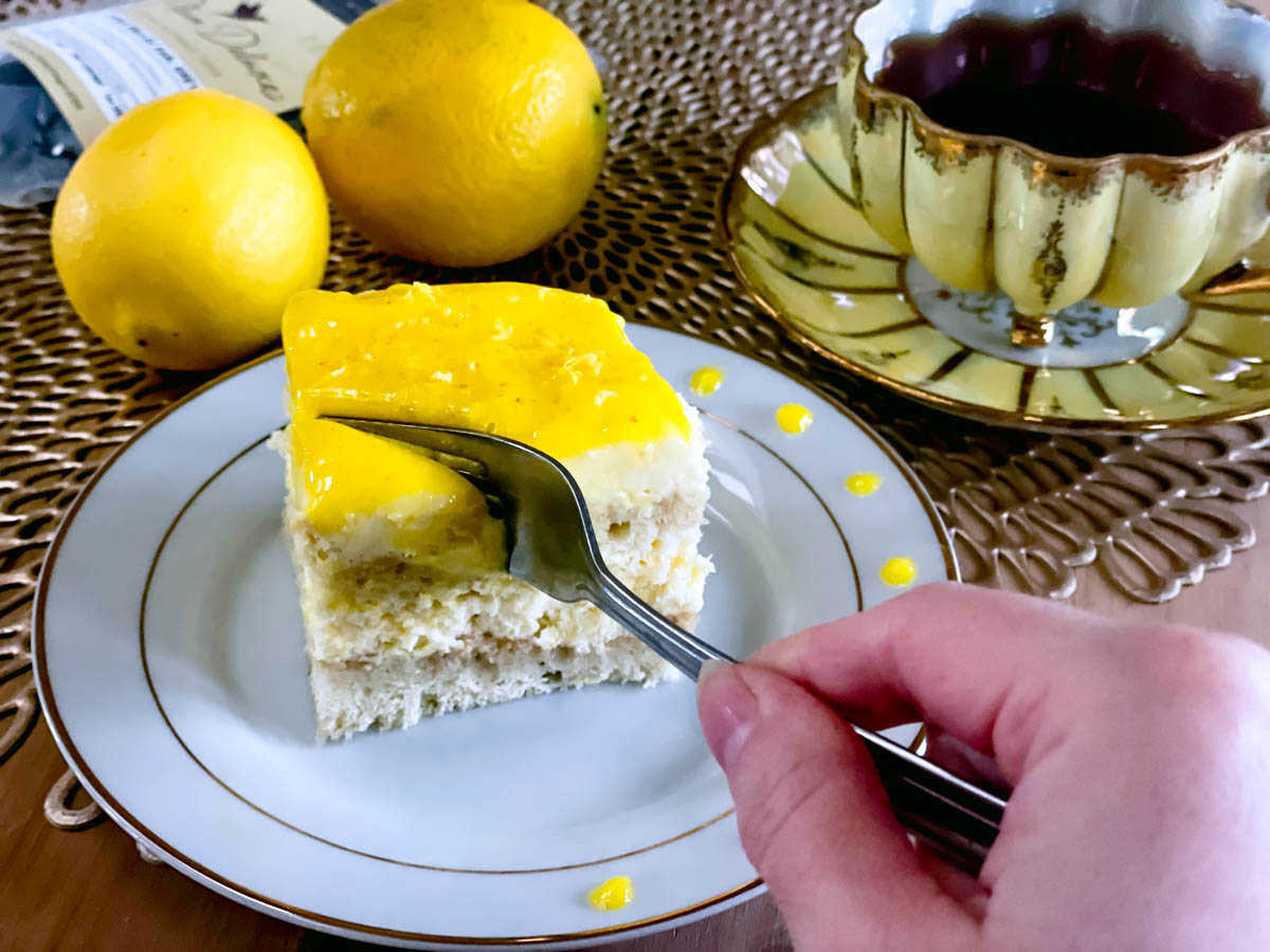 A fork smoothly cuts through the slice of lemon curd tiramisu.