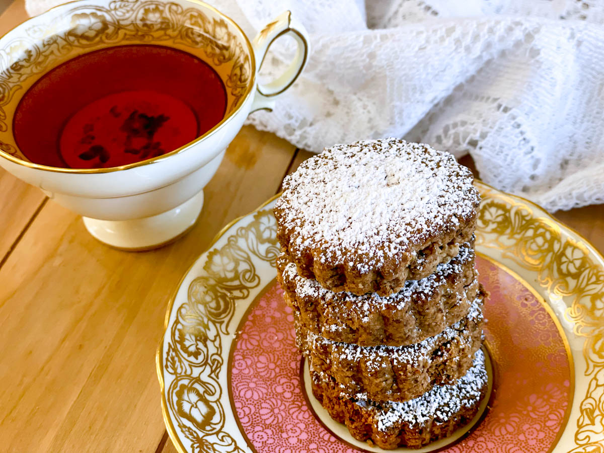 A tower of four stacked Polvorones accompanied by a cup of tea.