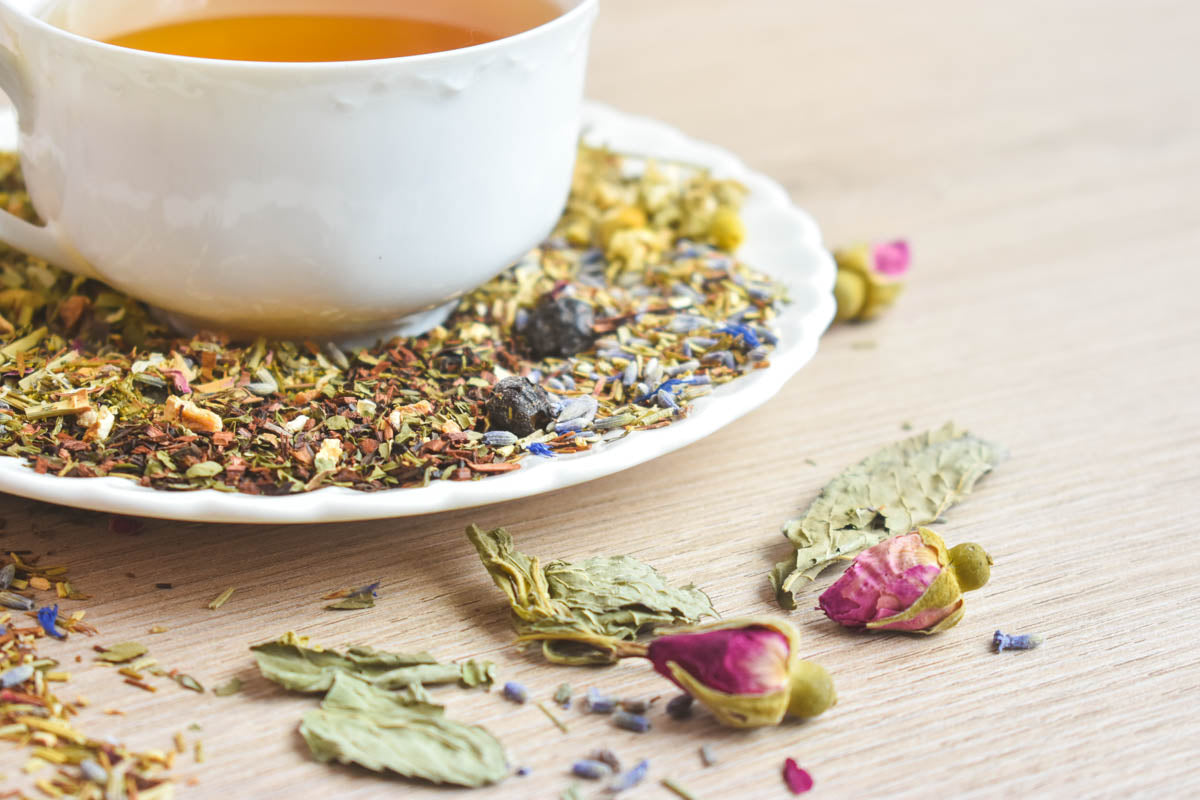 A side-on close-up of various loose-leaf herbal teas with rose hips occupying a prominent place.