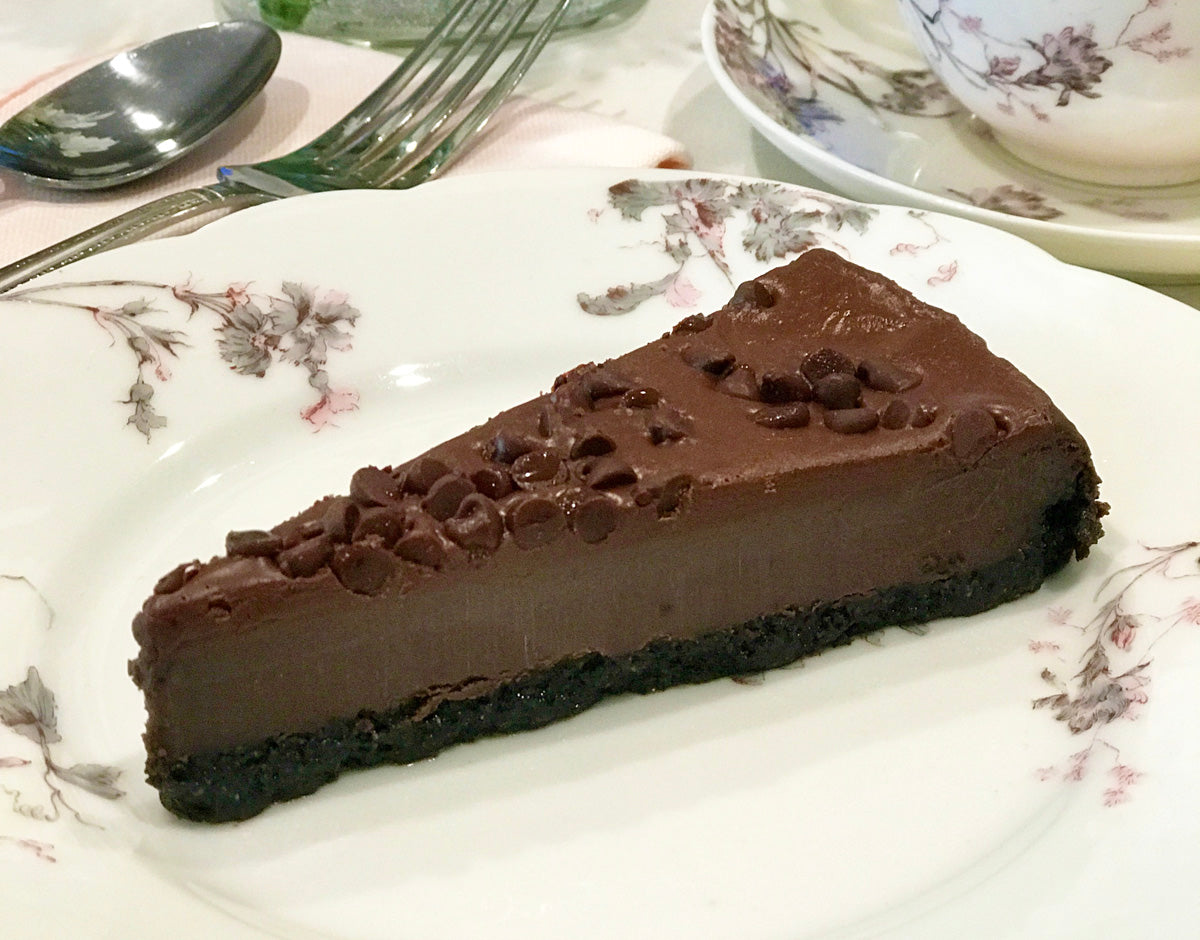 A slice of chocolate mint chip cheesecake is served on a white and purple floral plate.