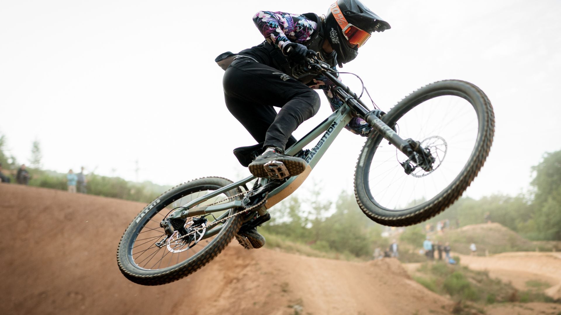 A mountain biker mid-air during a jump, wearing specialized MTB pants that demonstrate their flexibility and robustness, perfectly suited for high-adrenaline, airborne maneuvers