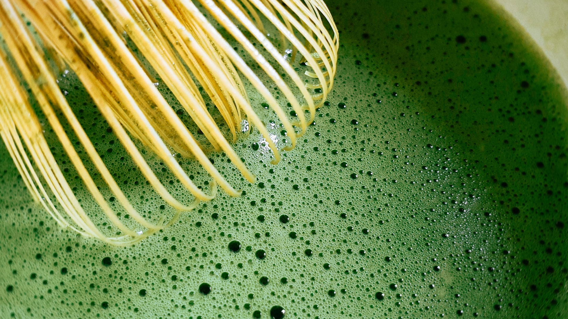 Close up of bamboo matcha whisk and matcha tea
