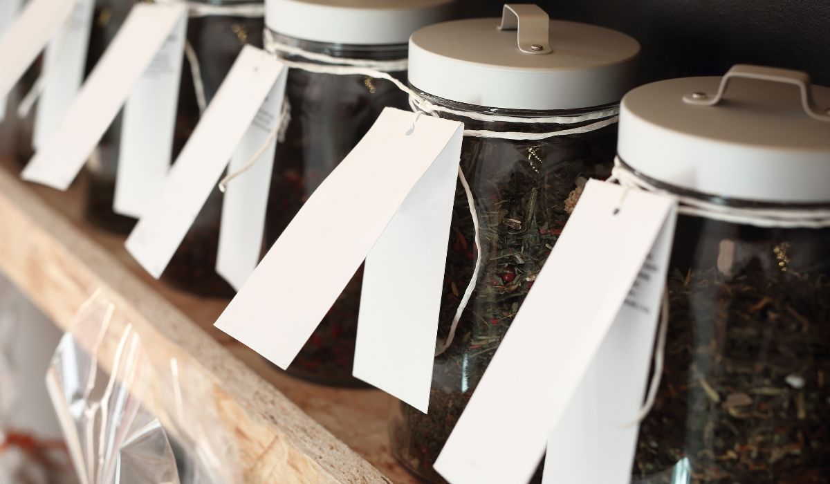 A photo of a tea shop's shelves, filled with various types of loose leaf green teas, each with clear labeling.