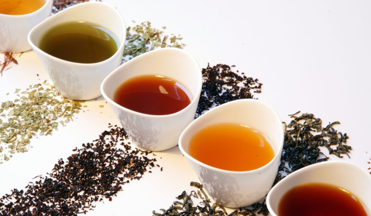 A variety of loose green green teas on a white bench