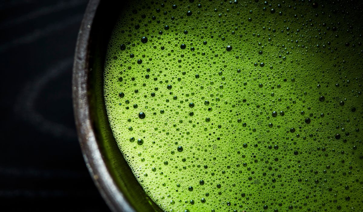 A frothy bowl of matcha green tea in a black chawan matcha bowl