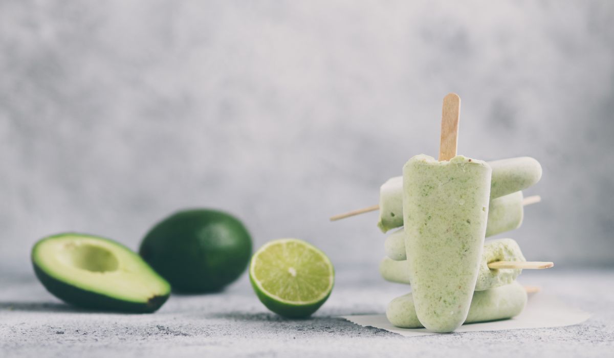 Matcha avocado lime popsicles next to cut lime and avocado for display