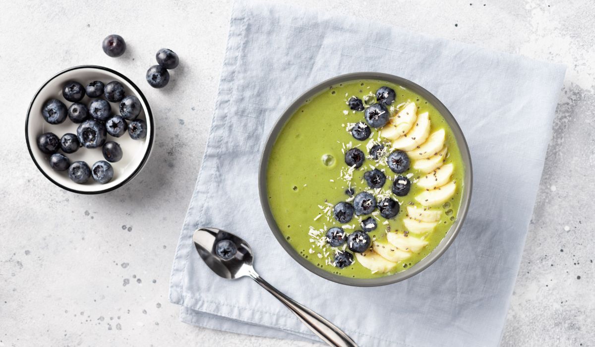 Matcha smoothie bowl topped with sliced banana and blueberries