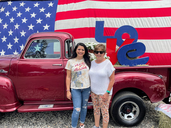 Alison Rose and her Mom at pro.found market in front of a red truck and flag