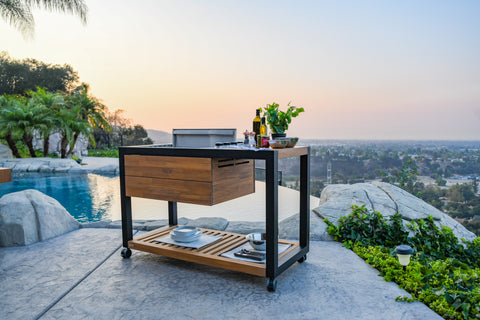 Stylish Grill Island outdoor kitchen with durable matte black aluminum frame and Grade-A teak, featuring a grill, plancha, and lower shelf for propane storage.