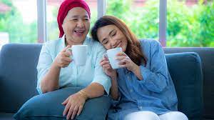 Mum wearing a scarf and daughter drinking tea and laughing