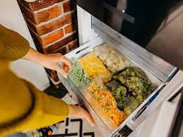 Lady opening a freezer drawer of food