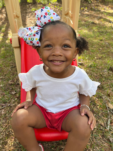 Little girl playing wearing a grosgrain Wee Ones headband with a large glittery pencil hair clip